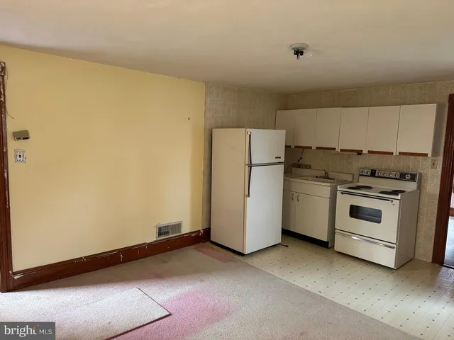 a view of a kitchen with refrigerator stove and white cabinets