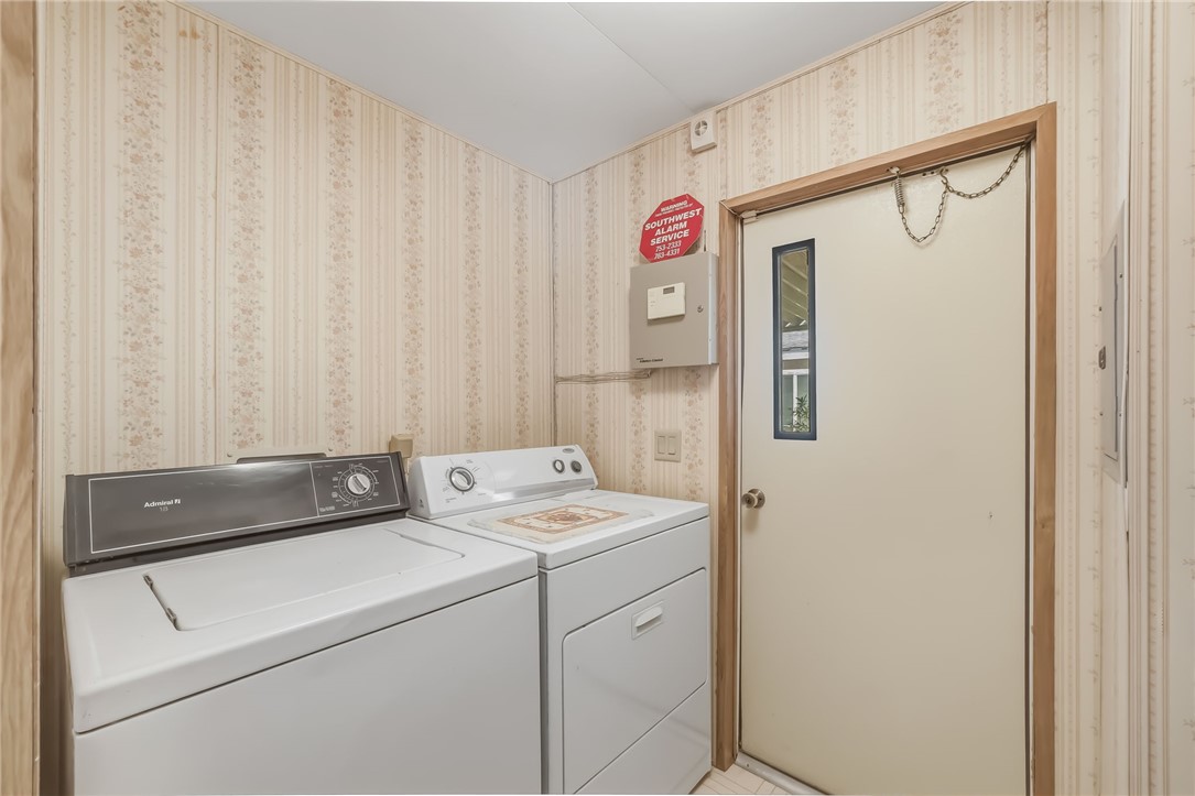 3880 Rising Sun Road Bullhead City, AZ 86442 - Photo 22 of 42 Dedicated laundry area featuring a washer and dryer, light-toned patterned wallpaper, and a cream-colored door with a rectangular window