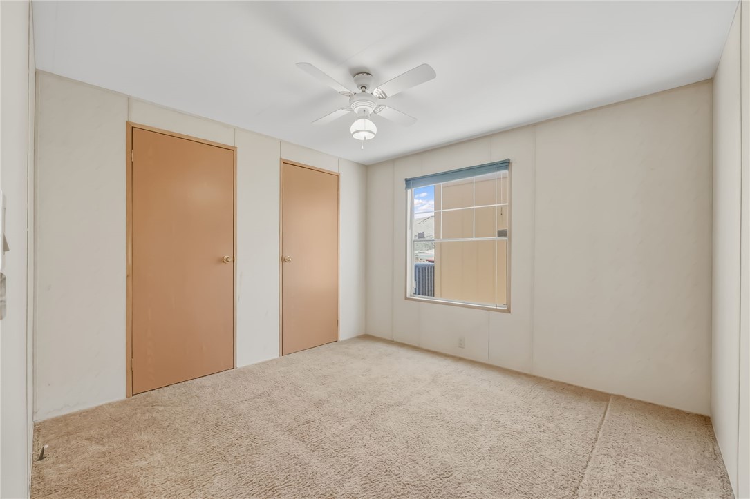 3880 Rising Sun Road Bullhead City, AZ 86442 - Photo 30 of 42 Carpeted room featuring a ceiling fan with integrated lighting, two panel doors, and a window with blinds