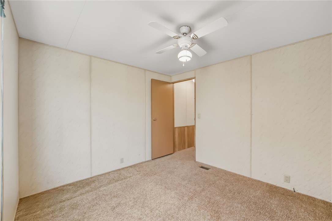3880 Rising Sun Road Bullhead City, AZ 86442 - Photo 31 of 42 Carpeted interior space featuring a ceiling fan with integrated lighting, neutral wall finishes, a solid core door, and baseboard trim