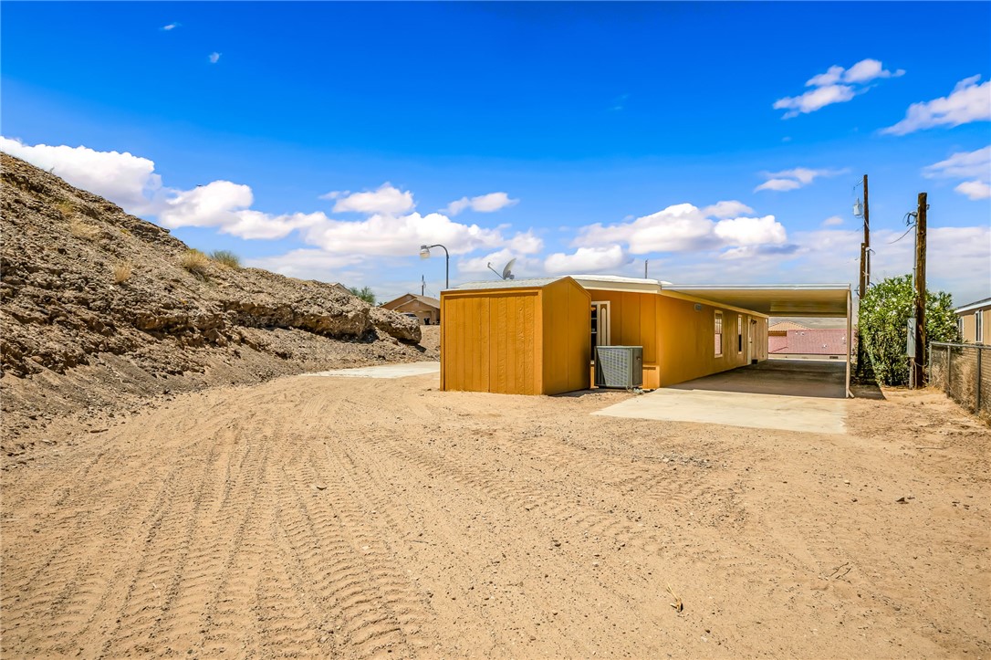 3880 Rising Sun Road Bullhead City, AZ 86442 - Photo 7 of 42 Single-story residence featuring a carport, exterior shed, and a large unpaved lot