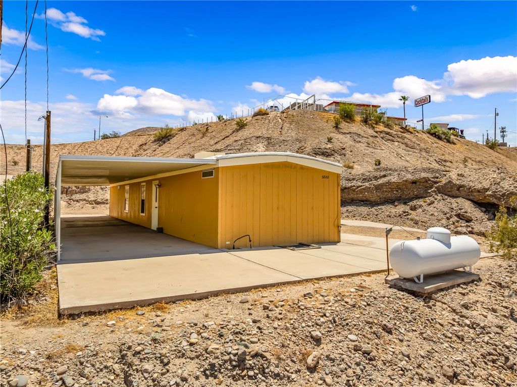 3880 Rising Sun Road Bullhead City, AZ 86442 - Photo 9 of 42 Single-story residence featuring a yellow exterior, a covered carport, and a white entry door