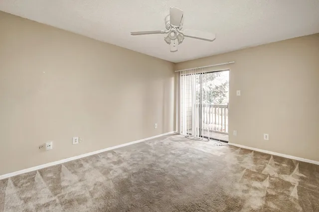 an empty room with windows and chandelier fan