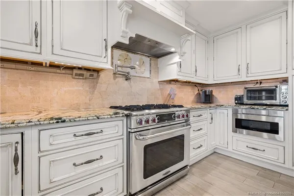 a kitchen with granite countertop white cabinets and appliances