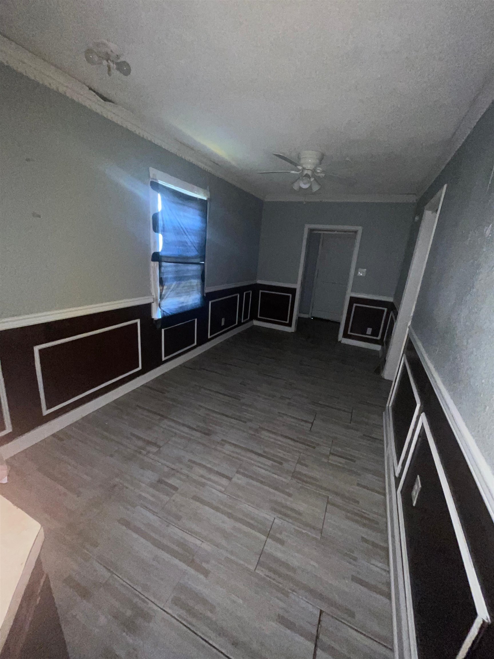 271 West Brooks Road Memphis, TN 38109 - Photo 9 of 17 Unfurnished room featuring wainscoting, a decorative wall, light wood-style flooring, a ceiling fan, and a textured ceiling