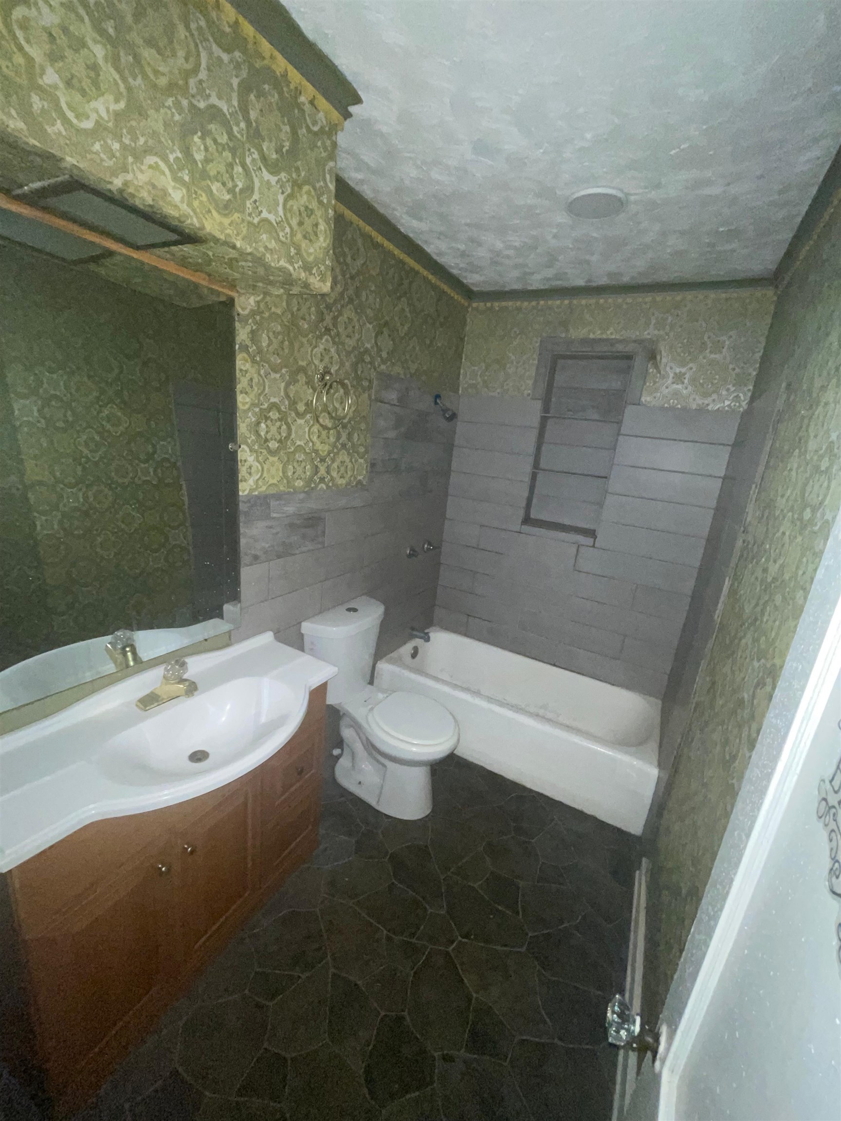 271 West Brooks Road Memphis, TN 38109 - Photo 10 of 17 Bathroom featuring vanity, bathtub / shower combination, wallpapered walls, a textured ceiling, and a wainscoted wall