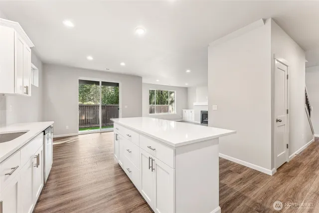 a large white kitchen with wooden floor and a sink
