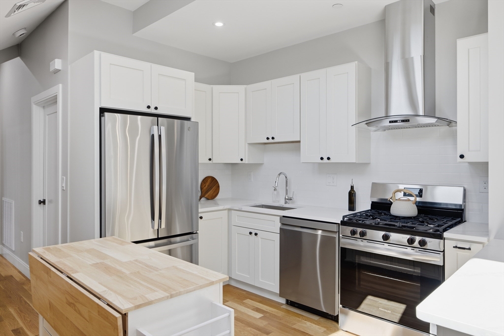 174 Walnut Street, Unit 3 Somerville, MA 02145 - Photo 24 of 38 a kitchen with stainless steel appliances a stove a sink and cabinets