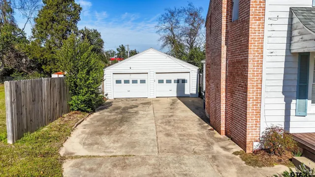 a view of a white house with a yard and wooden fence