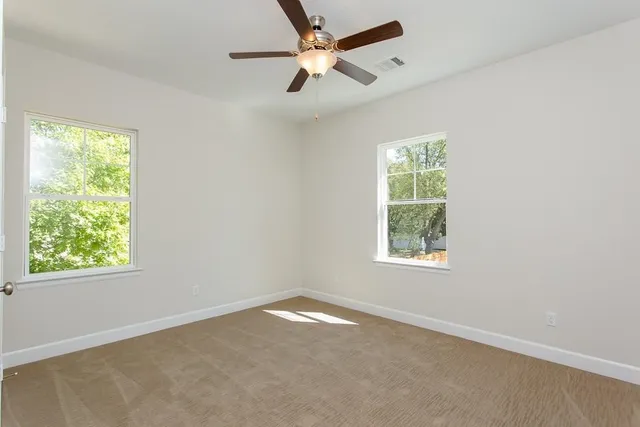an empty room with a window and a fan