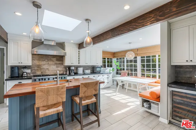 a kitchen with stainless steel appliances granite countertop a stove top oven a sink a dining table and chairs with the wooden floor