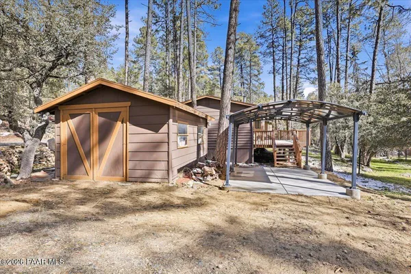 a backyard of a house with table and chairs under an umbrella