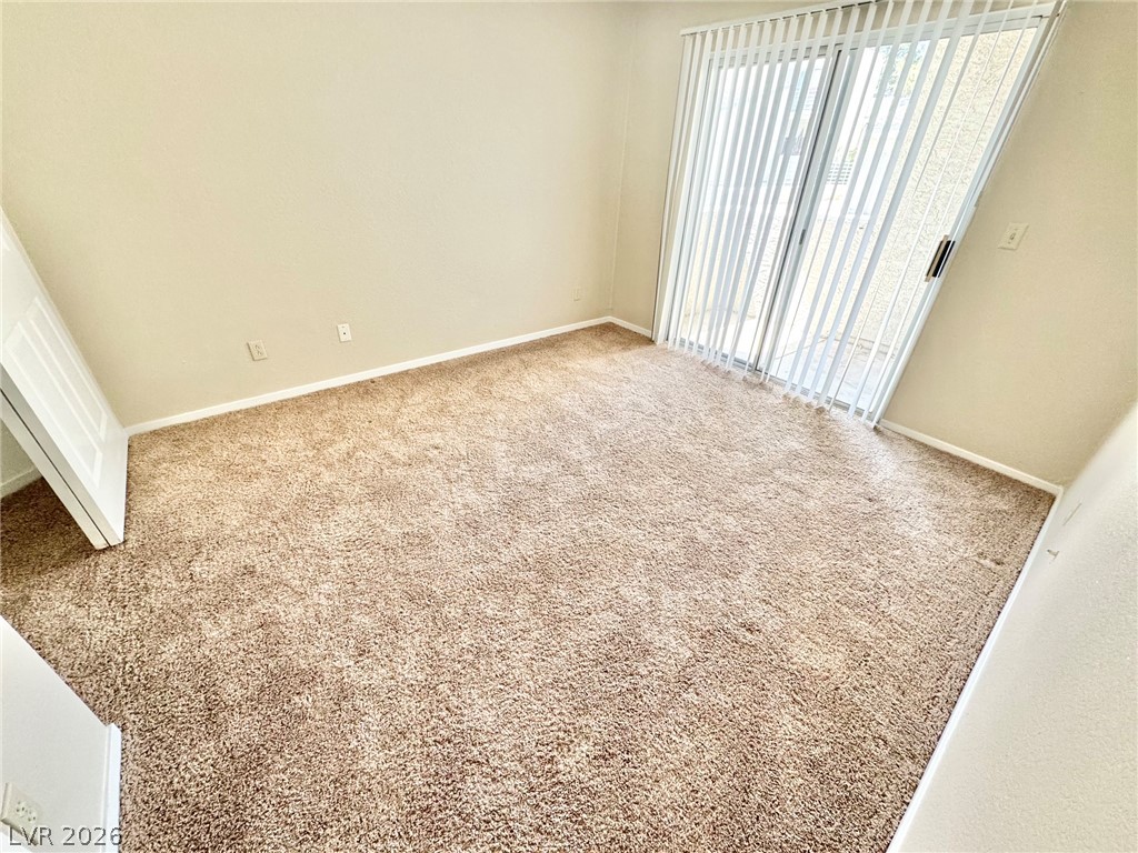 6250 West Flamingo Road, Unit 109 Las Vegas, NV 89103 - Photo 12 of 18 A well-lit bedroom features plush carpeting and convenient sliding door access to an outdoor space.