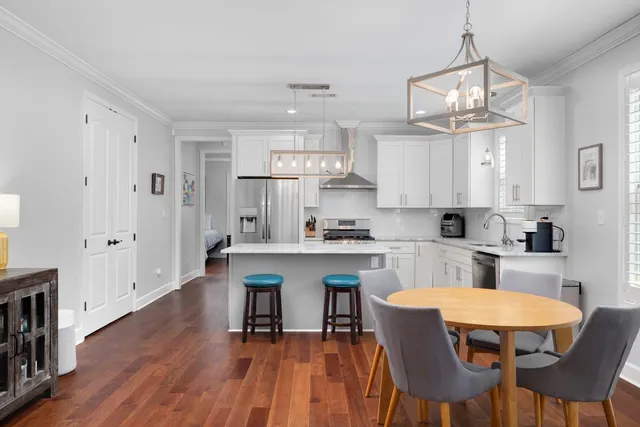 a kitchen with stainless steel appliances a dining table chairs and white cabinets