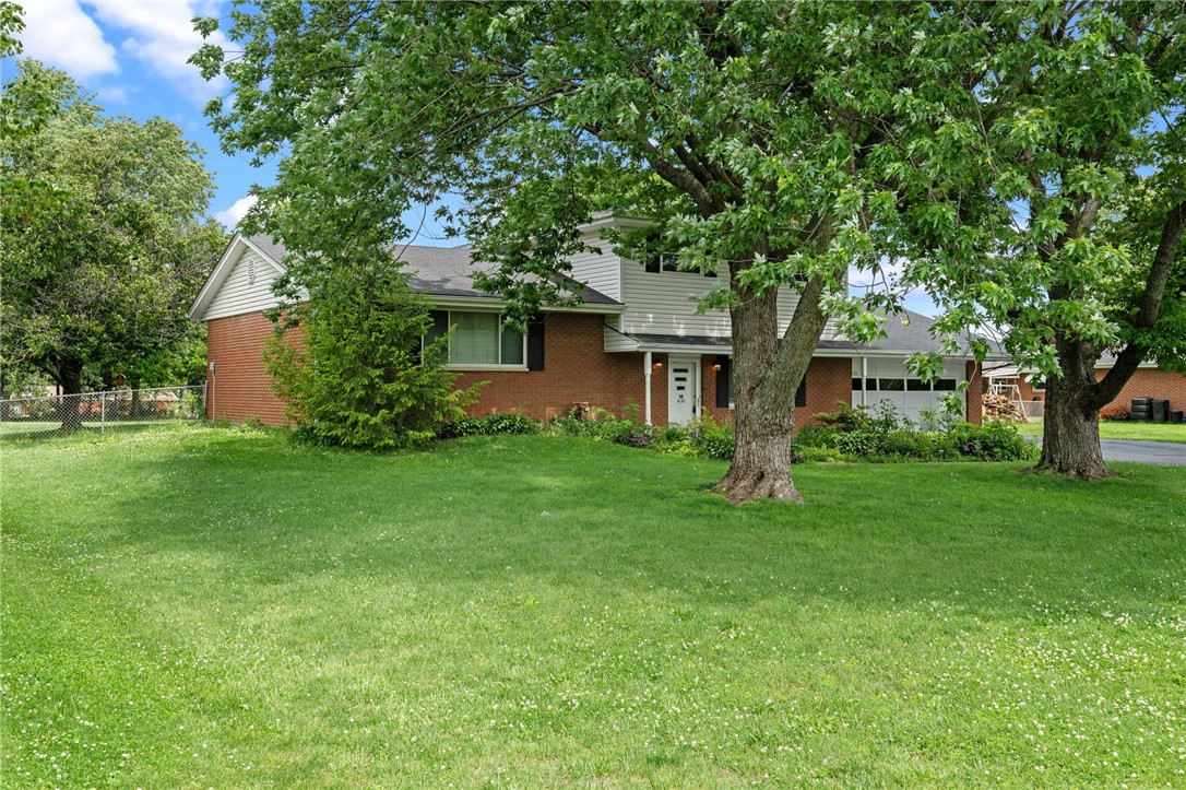 Mature trees frame a charming home with a spacious lawn and classic brick accents.