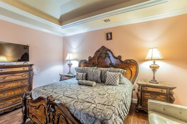 a bedroom with a bed and a flat tv screen on dresser