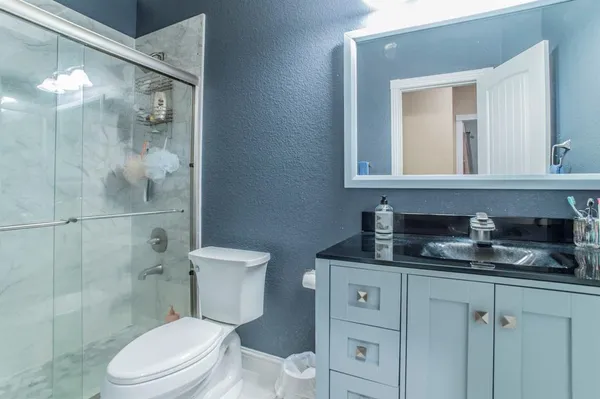 a bathroom with a granite countertop toilet sink and mirror