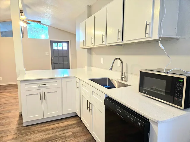 a kitchen with stainless steel appliances granite countertop a sink dishwasher a stove and a microwave oven with white cabinets