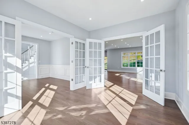 a view of an empty room with wooden floor and stairs