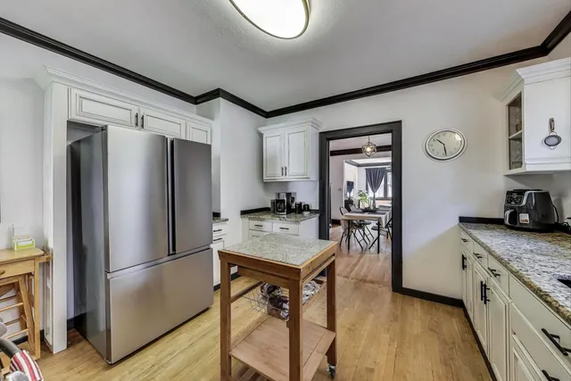 a kitchen with stainless steel appliances granite countertop a refrigerator a stove and a sink with wooden floor