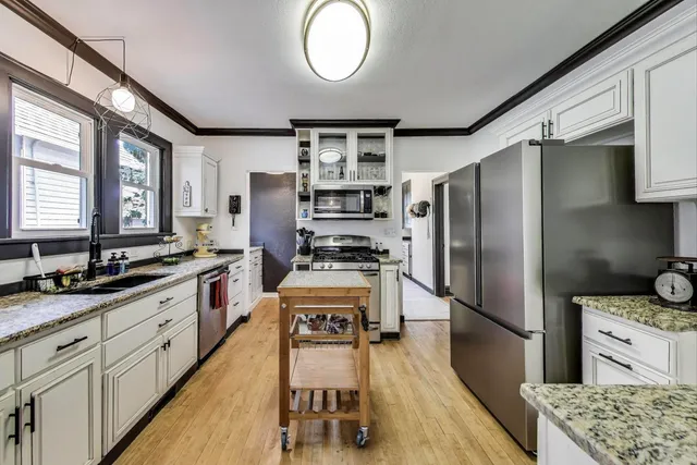 a kitchen with stainless steel appliances granite countertop a refrigerator a stove and a sink with cabinets