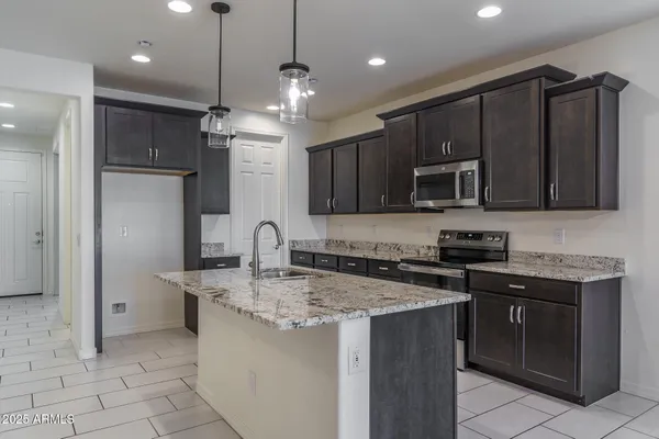 a kitchen with stainless steel appliances granite countertop a stove top oven a sink dishwasher a dining table and chairs