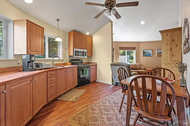 a kitchen with stainless steel appliances granite countertop a stove a sink dishwasher a dining table and chairs with wooden floor