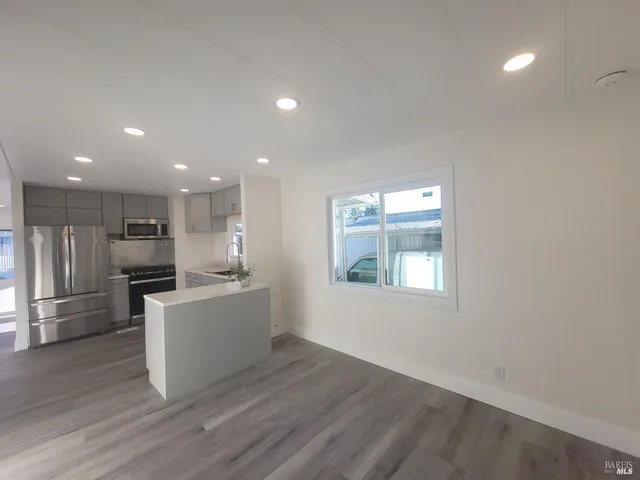 a large kitchen with a large counter top a sink stainless steel appliances and cabinets