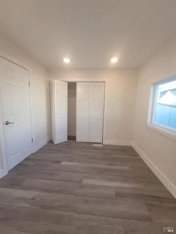 a view of an empty room with wooden floor and window
