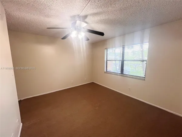 an empty room with windows and fan