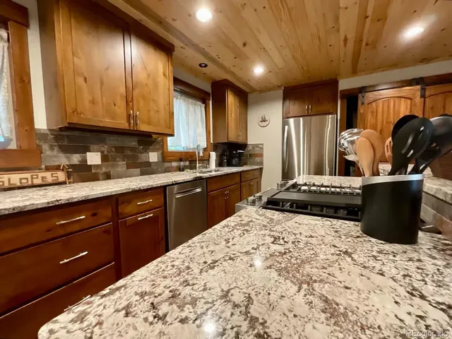a kitchen with stainless steel appliances kitchen island granite countertop a sink stove and cabinets