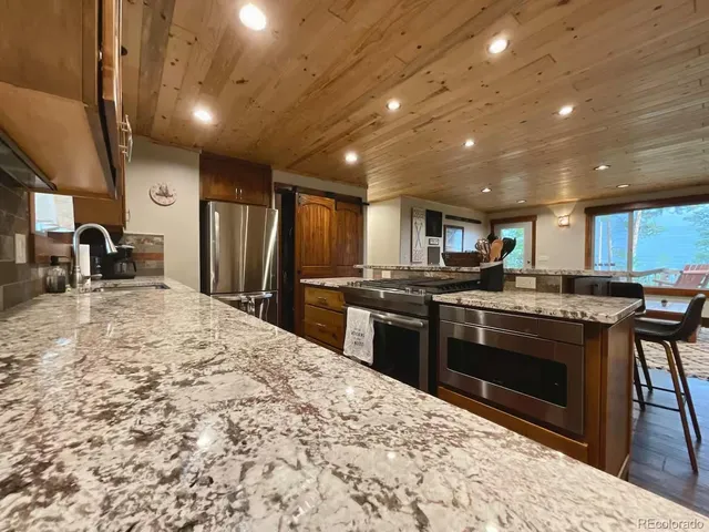 a kitchen with stainless steel appliances kitchen island granite countertop a sink stove and refrigerator