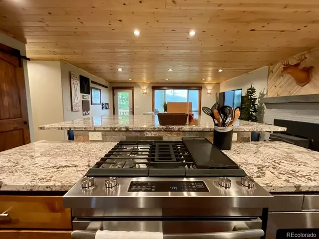 a kitchen with kitchen island granite countertop a stove and a sink