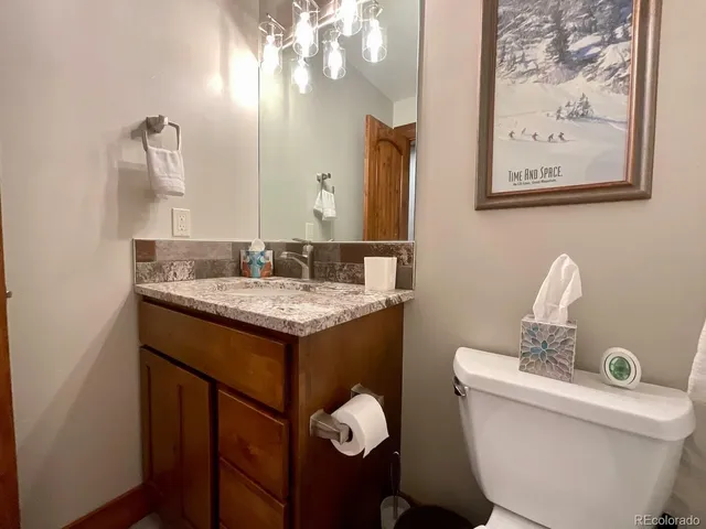 a bathroom with a granite countertop toilet sink and mirror