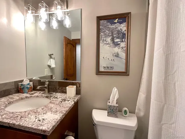 a bathroom with a granite countertop sink a toilet and a mirror