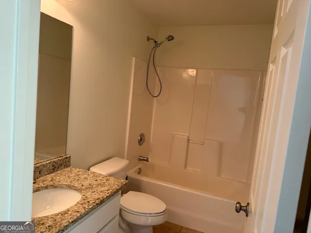 a bathroom with a granite countertop bathtub shower and toilet