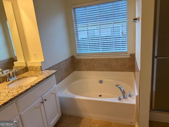 a bathroom with a granite countertop sink and a bathtub
