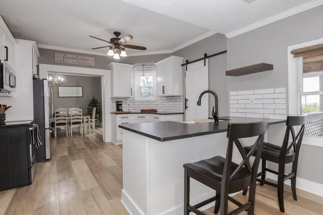a kitchen with stainless steel appliances white cabinets and wooden floor