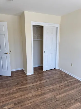 a view of an empty room with wooden floor and closet