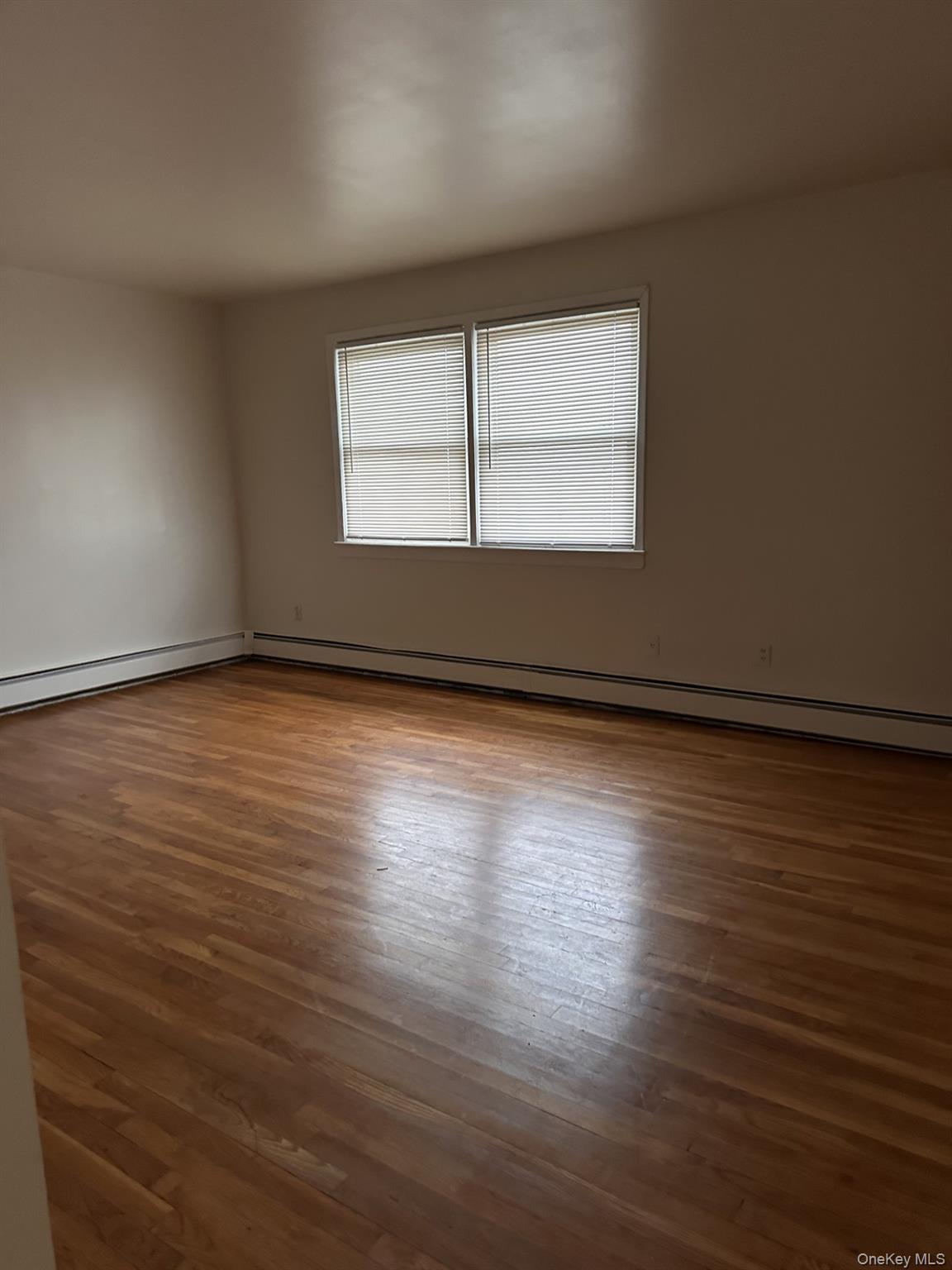 45 Benedict Avenue, Unit 5 Valley Stream, NY 11580 - Photo 3 of 7 an empty room with wooden floor and windows