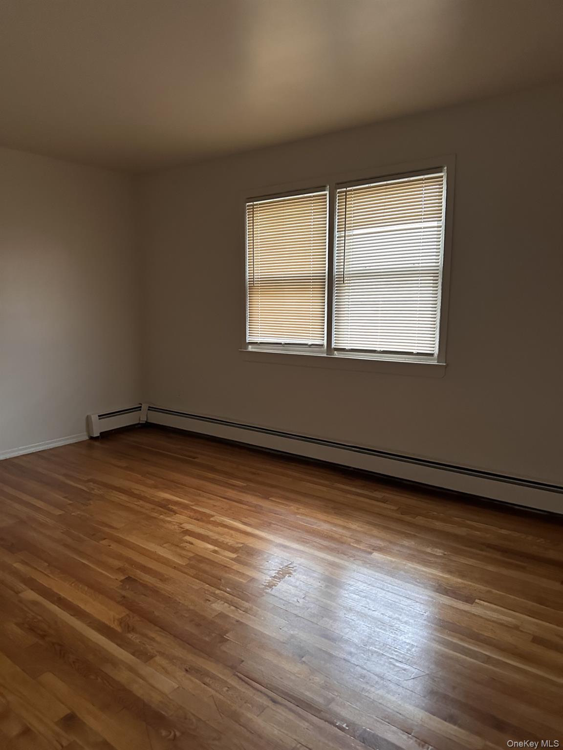 45 Benedict Avenue, Unit 5 Valley Stream, NY 11580 - Photo 4 of 7 a view of an empty room with wooden floor and a window