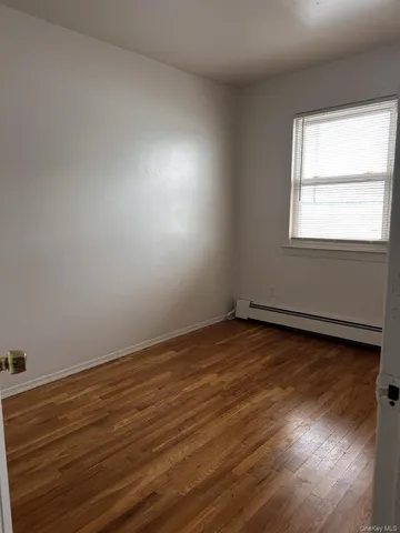 a view of an empty room and wooden floor and window