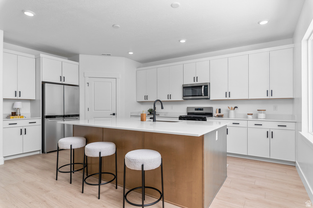 1352 West 2350 South, Unit 18 Perry, UT 84302 - Photo 7 of 26 Modern kitchen featuring a central island with a wood-finish base, white countertop, and stainless steel appliances