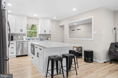 a kitchen with stainless steel appliances granite countertop a stove a sink dishwasher and a refrigerator with wooden floor