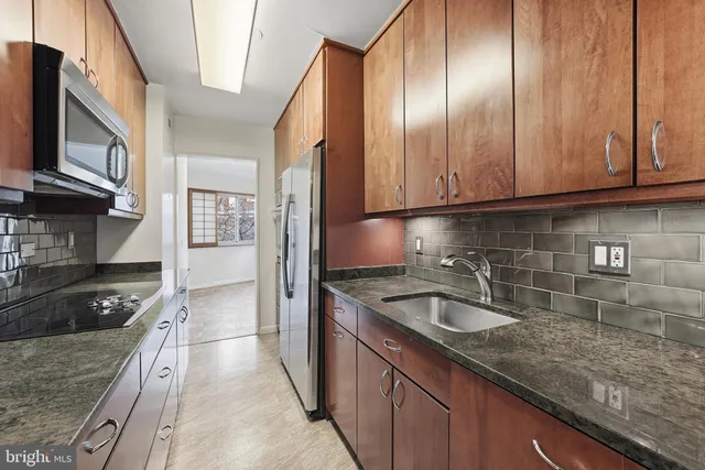 a kitchen with granite countertop stainless steel appliances a sink a stove and cabinets