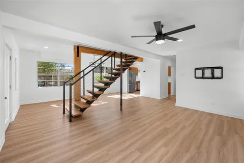 a view of an empty room with wooden floor and stairs