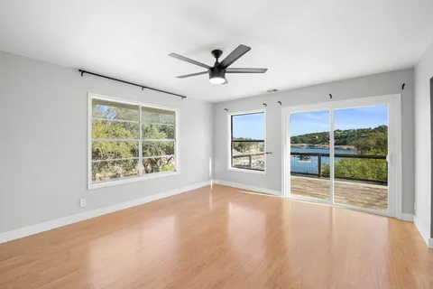 a view of an empty room with a window and wooden floor