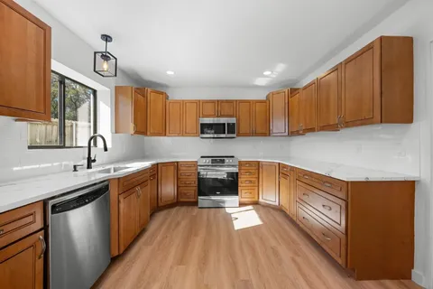 a kitchen with stainless steel appliances a sink cabinets and wooden floor