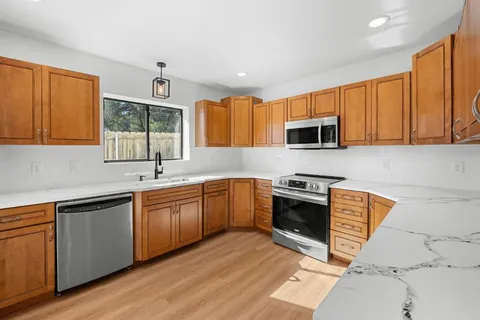 a kitchen with stainless steel appliances granite countertop wooden cabinets granite counter tops and a hard wood floors