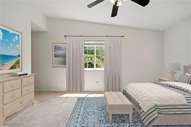 a bedroom with a large bed and a chandelier fan